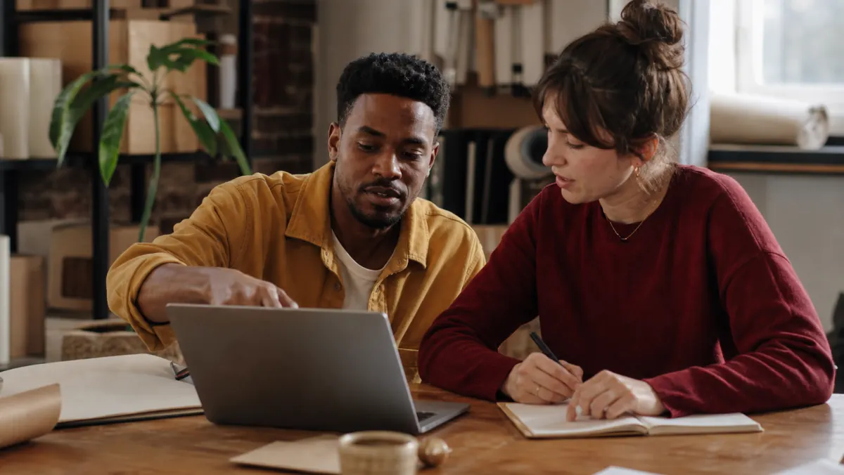 Two business operators reviewing notes together at a laptop
